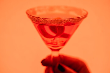 close up of margarita cocktail with ice cubes and salt in female hand on orange