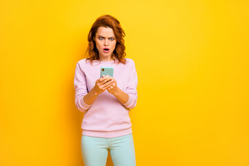 It can't be true Photo of speechless lady open mouth hold telephone reading negative bad comments own blog wear pink pullover green pants isolated yellow color background