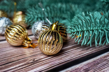 Close up golden Christmas toys on a wooden background with Christmas tree branches