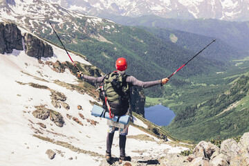 Happy tourist in high mountains with large backpack and sticks