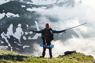 Traveler alone tourist in the mountains with a big backpack and sticks.