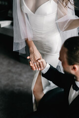 The groom in a suit holds the hand of the bride in a wedding dress