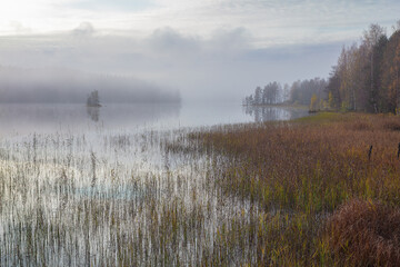 Autumn, foggy morning, over the lake, in the distance you can see a small island. Finland, Scandinavian nature.