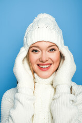 smiling beautiful woman in winter white outfit isolated on blue