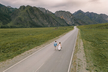 Drone view of a wedding couple on the road among the mountains