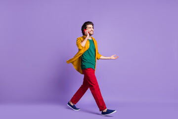 Fototapeta na wymiar Full length photo portrait of man talking over phone walking isolated on vivid violet colored background