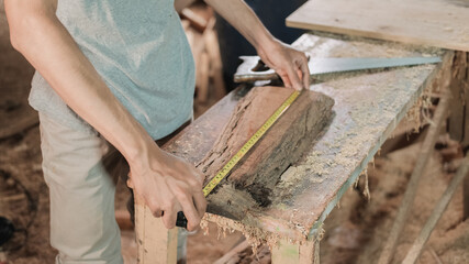 close up carpenter's hand measuring wood using carpenters ribbon ruler at the workshop