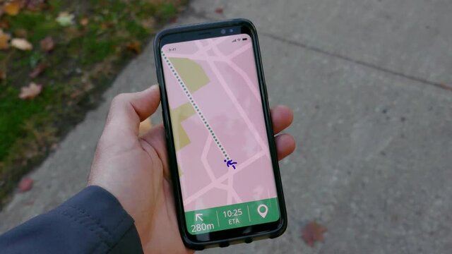 Walking outside holding a mobile phone showing a GPS app. POV concept of walking with a smartphone.
