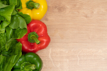 Tricoloured peppers and green lettuce leaves on cutting board