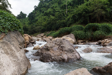 Fototapeta na wymiar View of a little cascade falls of water over mountain river rocks.
