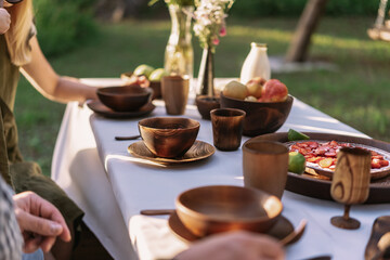Table served outside with wooden dishes and pie and pears