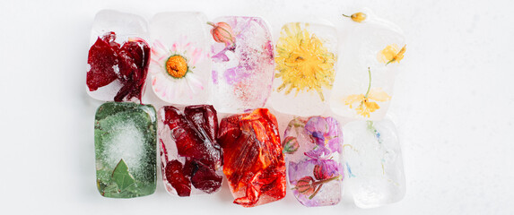 Ice cubes with flowers inside on white background. Wide, cinema, banner format
