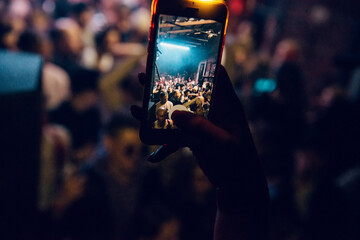 A woman's hand with phone over the party crowd