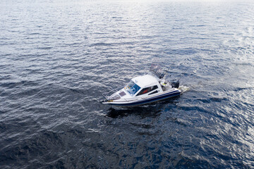 Aerial view fisherman on boat at the ocean. Top view beautiful seascape with the fishing boat. Aerial view fishing motor boat with angler. Ocean sea water wave reflections. Motor boat in the ocean.