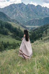 Girl in a poncho in a green valley against the backdrop of mountains in altai