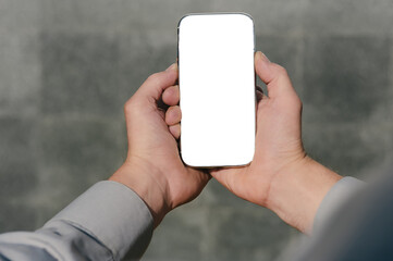 Close up, mock up smartphone, in hands, of a person. against the background of a concrete wall.