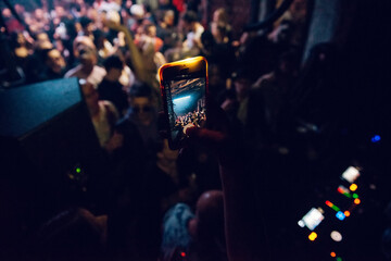Fototapeta na wymiar Woman holding smartphone and taking a video in nightclub