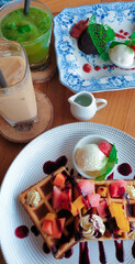 Dessert waffle with tropical fruits and chocolate sauce and ice cream, with ice cappuccino 