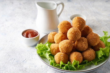 cheese balls, appetizer with herbs and sauces in a plate on a gray table