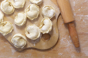Closeup on semi-finished pelmeni dumplings on the wooden board.