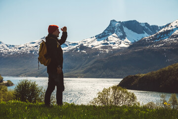 Fototapeta na wymiar Young man with a backpack standing on the background of mountains and lake. Space for your text message or promotional content. Travel lifestyle concept