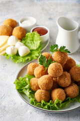 cheese balls, appetizer with herbs and sauces in a plate on a gray table