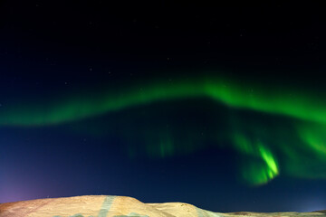 Aurora borealis in winter time. Northern lights. Sky with stars and northern lights and winter landscape. 