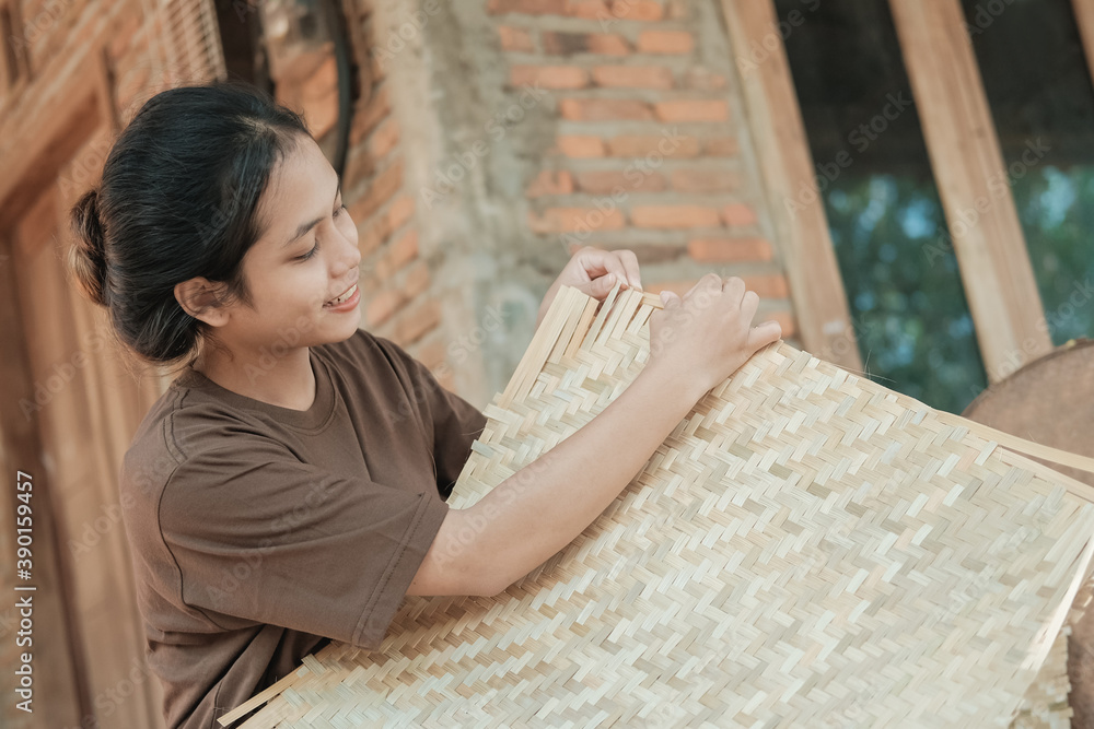 Wall mural side view of female workers smiling while working to make bamboo mats at home