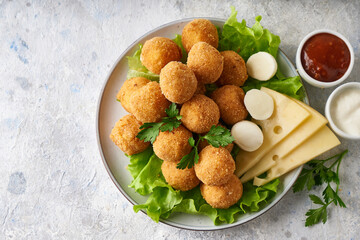 cheese balls, appetizer with herbs and sauces in a plate on a gray table