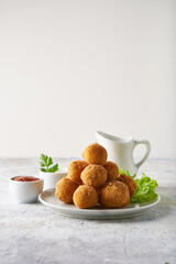 cheese balls, appetizer with herbs and sauces in a plate on a gray table