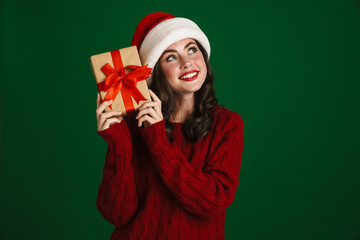 Charming happy girl in Santa Claus hat posing with Christmas gift