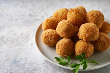 Fried cheese balls, appetizer with herbs and sauces in a plate on a gray table Copyspace