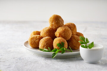 cheese balls, appetizer with herbs and sauces in a plate on a gray table