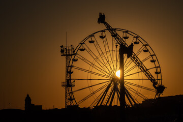 Ferris wheel in amusement park at sunset.