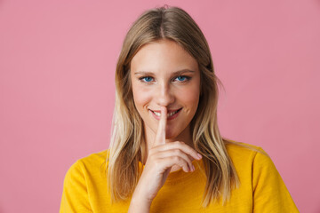 Cheerful beautiful girl showing silence gesture at camera