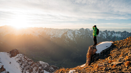 Climber looking at a snowy mountain landscape in a sunny winter day. Travel man tourist alone on...