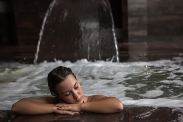 Calm brunette chilling in bubbling water of spa pool