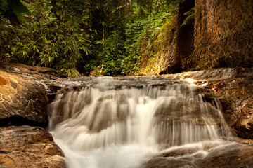 view of a waterfall surrounded by rocks and plants in the background