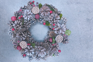 Christmas wreath made of pine cones on a concrete background, horizontal photo in cold silver colors