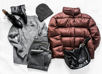 Women's winter autumn clothing - down jacket, jeans, hat, sweater and boots on a light background, top view. Fashion concept © okkijan2010