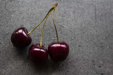 Juicy cherry close up photo. Water drops on fresh berries. Dark grey textured background. Healthy eating concept. 