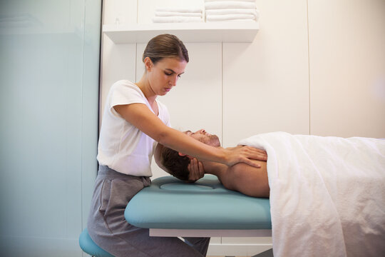 Female physiotherapist giving head massage to male patient