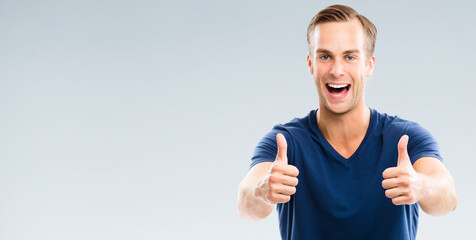Portrait of cheerful young man showing okay ok gesture, isolated over grey background. Emotions and success studio concept. Copy space for some text.