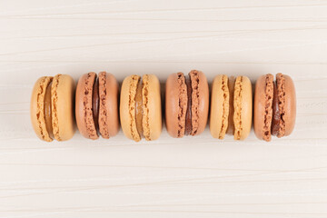 Six coffee and chocolated flavoured macaroons on vinyl background
