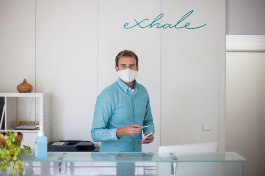 young man wearing mask at the reception of modern fitness club during covid-19