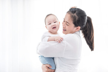 Asian woman smile and holding son baby in her arms. Happy family. Asia mother lifting and looking her adorable kid baby on white. love people concept