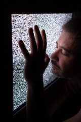 hombre apoya la cara en tv de tubo sin señal con los ojos serrados y manos