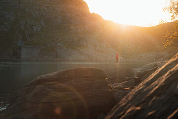 Kid walking on top of a rock during sunset in a lake