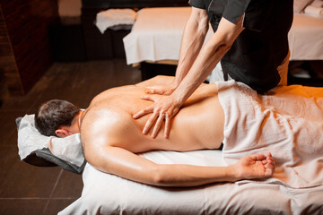 Fototapeta premium Man receiving a deep massage on his back from professional therapist at luxury spa salon
