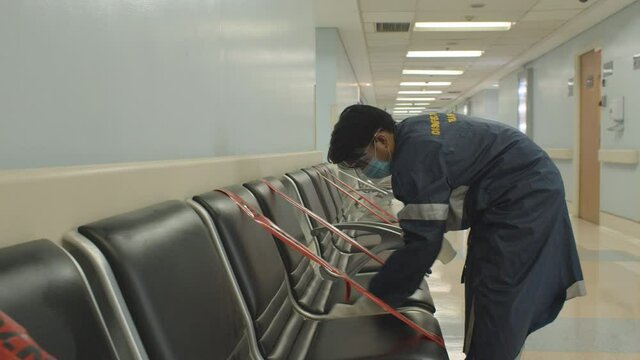 Man Disinfecting And Cleaning Chairs To Avoid The Spread Of Coronavirus Inside The Hospital